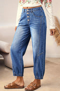Person wearing blue jeans with a white top and brown sandals in a room setting.